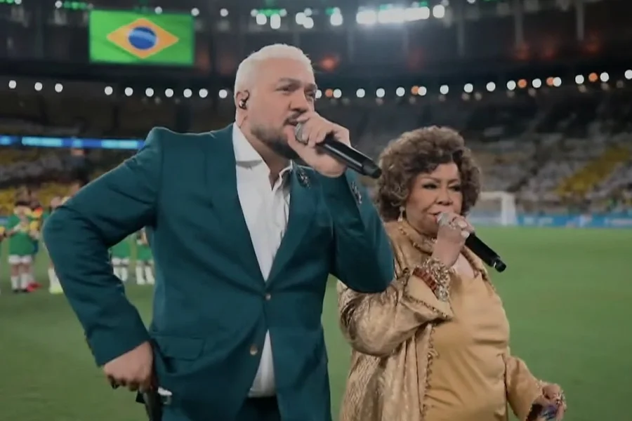 Belo e Alcione viram meme ao cantarem em amistoso: “Deixaram o hino morrer”